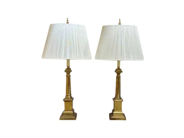 A pair of Neoclassical Brass Table Lamps with string shades, featuring ornate gold bases and white fabric shades, set against a plain white background.