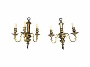 The image shows a pair of classic-style, three-arm brass wall sconces by EF Caldwell, each featuring candle-shaped lights against a white background.