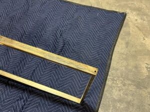 Metal frame resting on a blue quilted fabric on a concrete floor.