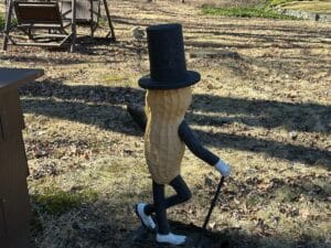 The Cast Iron "Life Size" Mr. Peanut Statue, complete with a top hat, cane, and gloves, is positioned outside with a swing visible in the background.