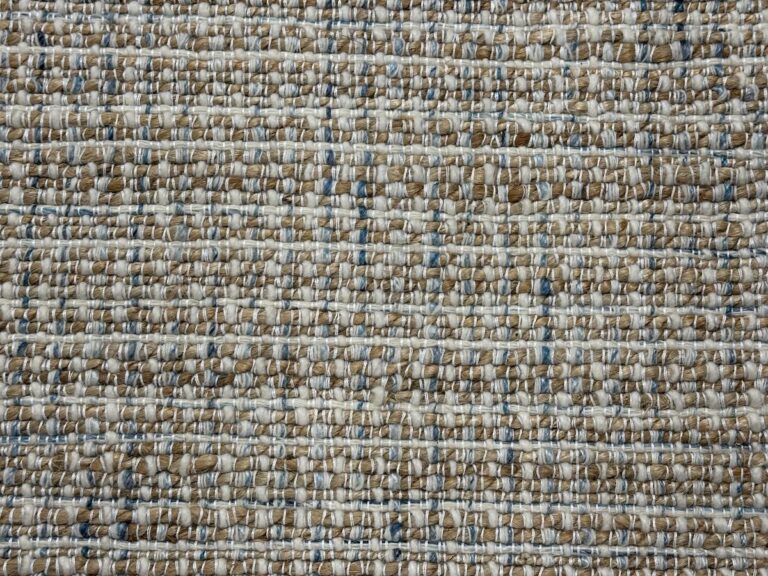 Close-up of a textured woven fabric featuring tan, light blue, and white threads to create a patterned surface on an 8 x 9 area rug.