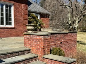 Brick patio featuring steps and a leafless tree, adorned with a set of three Vintage Rectangular Concrete Planters.