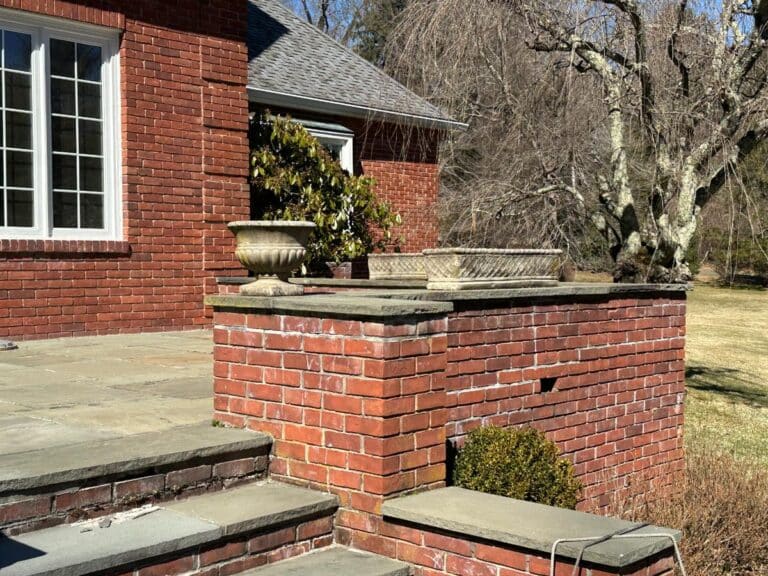 Brick patio featuring steps and a leafless tree, adorned with a set of three Vintage Rectangular Concrete Planters.