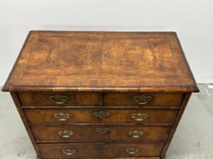 The Antique Burl Chest of Drawers features ornate handles and a rich wood grain pattern visible from the top view.