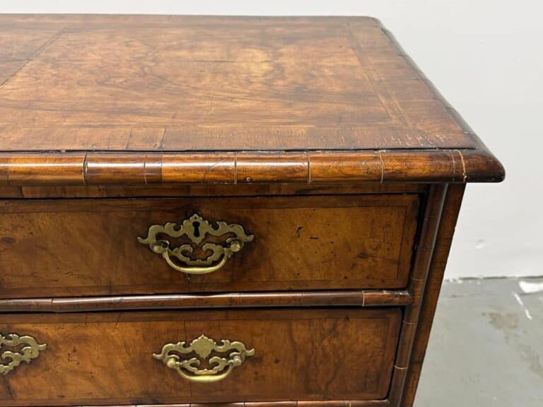 A close-up of the Antique Burl Chest of Drawers, showcasing its brass handles and intricate wood grain details.