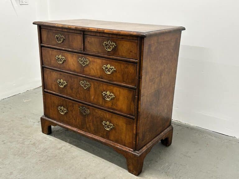 Antique Burl Chest of Drawers with ornate brass handles, placed against a plain white wall.
