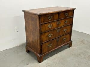 Antique Burl Chest of Drawers with four drawers and ornate handles enhances a minimalistic room.