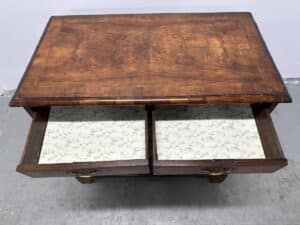 The Antique Burl Chest of Drawers features two open drawers lined with floral-patterned paper, displayed on a gray floor.