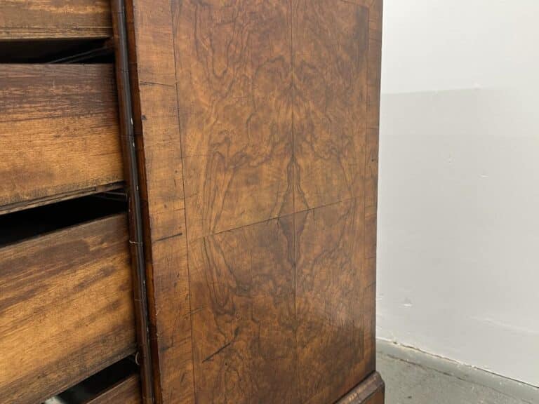 A close-up of the Antique Burl Chest of Drawers showcases its rich brown grains with a partially open drawer on the left.
