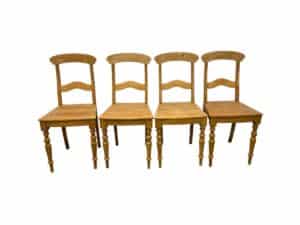 Four wooden chairs with simple, classic design, arranged in a row against a white background.