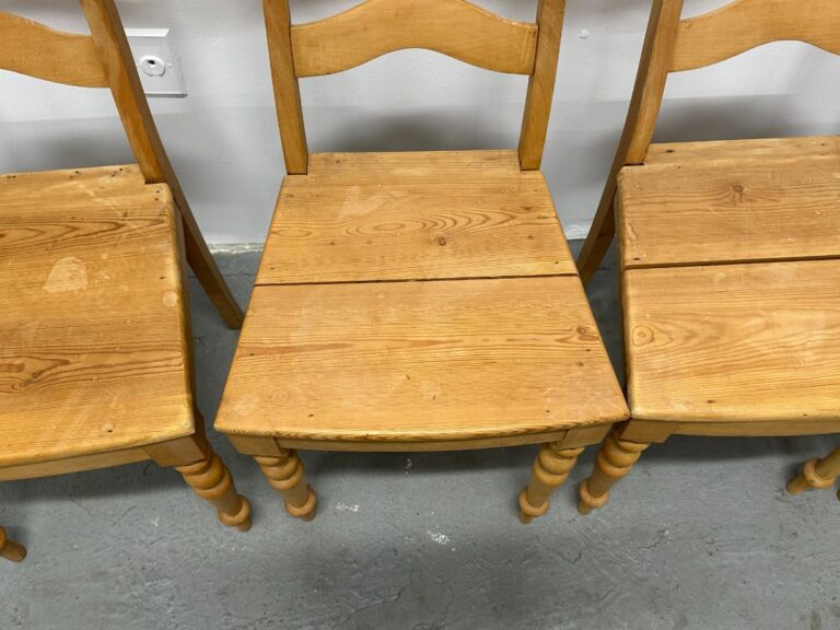 Three wooden chairs with curved backs and simple design, placed on a gray floor.