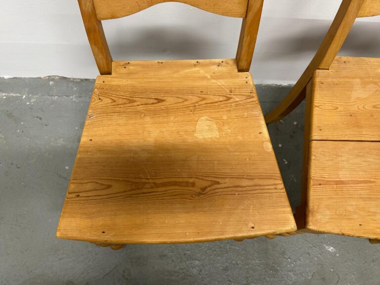 Wooden chair with a flat seat and a simple curved backrest on a gray concrete floor.