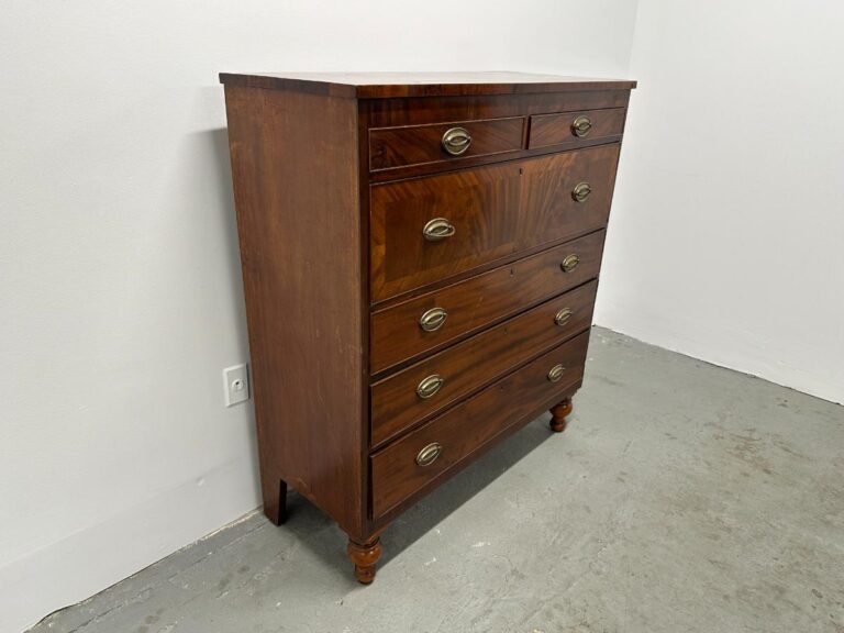 Vintage wooden dresser with six drawers and metal handles in a white, minimalistic room.