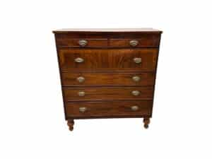 Wooden chest of drawers with six drawers and brass handles on short turned legs.