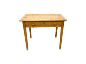 A well-used Antique Pine Writing Table featuring one drawer and round knobs on each side.