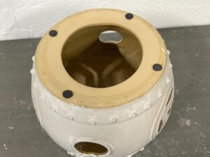 Top view of a ceramic lantern with a circular opening and decorative cutouts on a gray surface.
