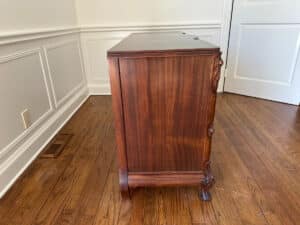 The French Carved Mahogany Vanity Ladies Desk sits against a light-colored wall in a room with wooden flooring.