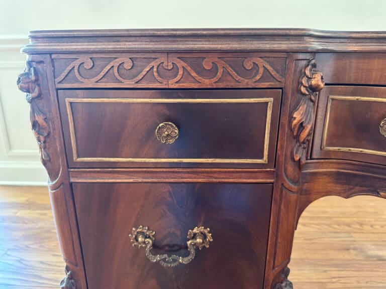 Close-up of the French Carved Mahogany Vanity Ladies Desk featuring vintage wooden furniture with ornate carvings and brass handles on a drawer and cabinet.