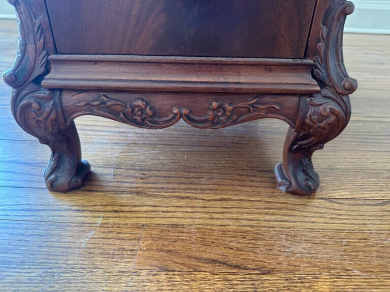 The French Carved Mahogany Vanity Ladies Desk stands on an ornate wooden leg with carved floral details atop a polished hardwood floor.