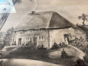 The Sussex House Etching, signed lower right, depicts a thatched-roof cottage enveloped by shrubbery with a person at the entrance.