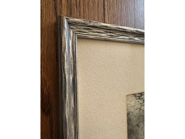 Close-up of a textured corner of the Sussex House Etching, signed lower right, featuring rustic details and mounted on a wooden wall.