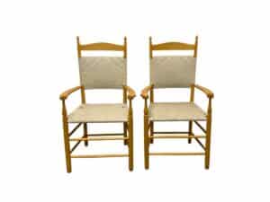 Two wooden chairs with woven backs and seats against a white background.