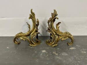 Pair of ornate, golden decorative brackets with leaf motifs, set against a plain background.