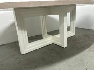 The Mr. Brown London Florence Dining Table sits on a gray floor, featuring a white surface and an L-shaped geometric leg design.