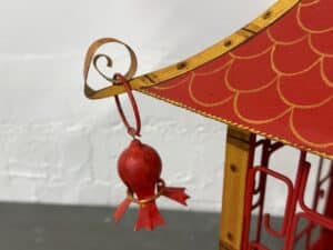 Close-up of a red decorative gazebo roof with a hanging pomegranate-shaped ornament.