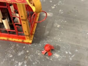 Red and yellow lantern with a detached red finial on a gray, textured surface.