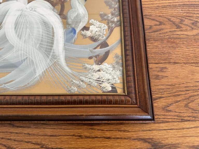 Close-up of the "Birds of Paradise Painting, Signed Lower Right," showcasing abstract white brushstrokes against a wooden floor background.
