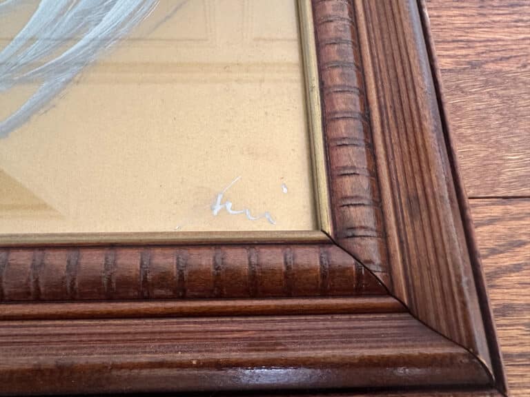 The Birds of Paradise Painting features a close-up view of a wooden picture frame corner and includes the artist's small, scribbled signature in the lower right.