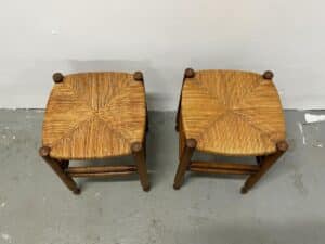 A pair of Rush Stools with woven straw seats, seen from above on a gray concrete floor.