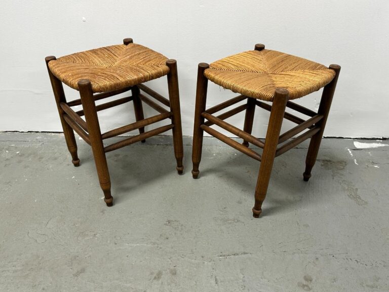 A pair of Rush Stools with woven seats is placed on a concrete floor against a white wall.