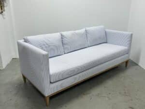 The Serena & Lily Barton Sofa features light blue stripes and wooden legs, sitting elegantly in a white room.