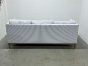 The Serena & Lily Barton Sofa features a back view showcasing light gray stripes and wooden legs, set in a white room.