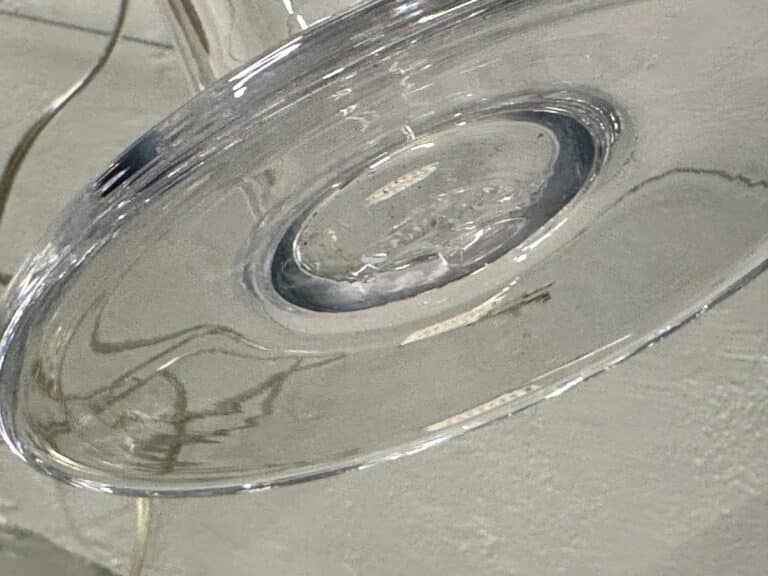 Close-up of Simon Pearce Glass Column Lamps featuring a clear glass design with circular, concave bases that create reflective patterns on a light surface.