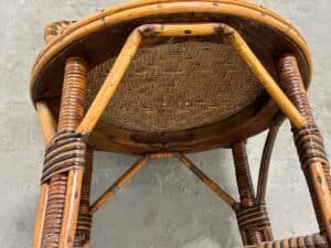 Underside view of a wooden woven chair with intricate patterns, resting on a gray concrete floor.