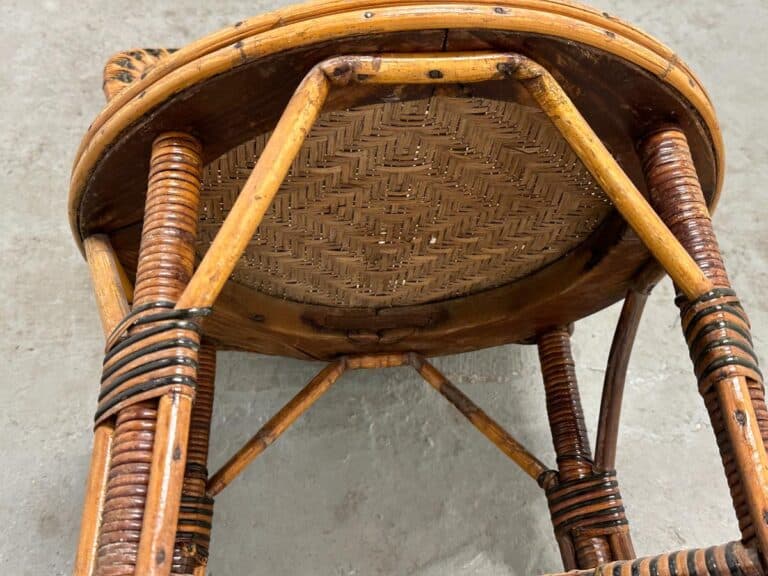 Underside view of a wooden woven chair with intricate patterns, resting on a gray concrete floor.