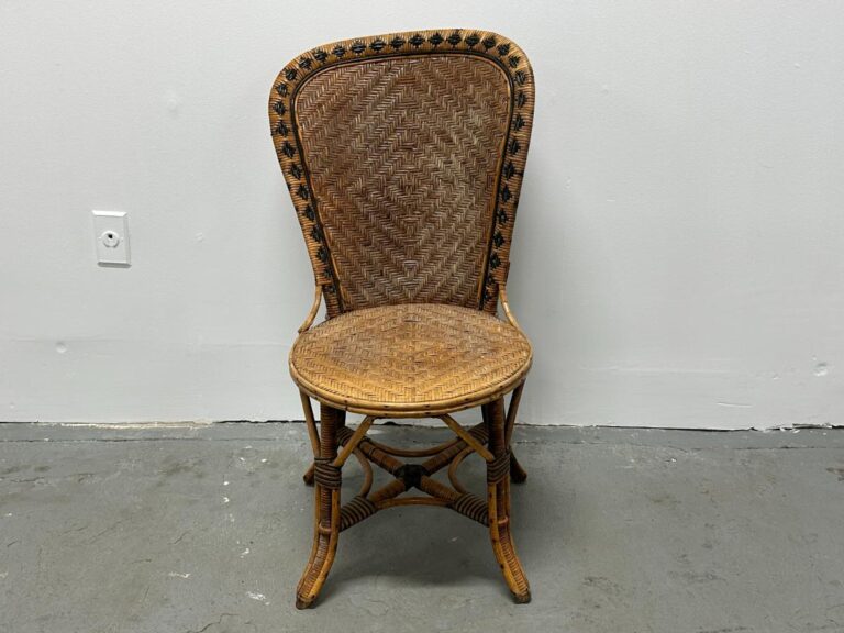 A wicker chair with a decorative backrest against a white wall on a gray floor.