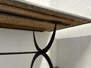 Close-up of a metal-framed table with a wooden top against a white brick wall.