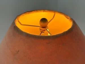 Close-up view of the inside top of a lampshade glowing with warm yellow-orange light.