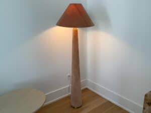 Tall floor lamp with a brown shade, standing in the corner next to a round table on a wooden floor.