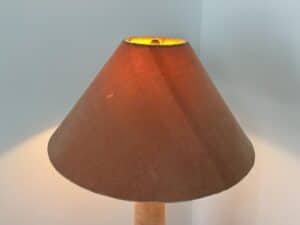 Brown lampshade lit from inside, casting a warm glow against light-colored walls in the corner.
