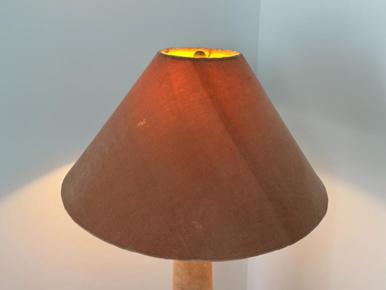 Brown lampshade lit from inside, casting a warm glow against light-colored walls in the corner.