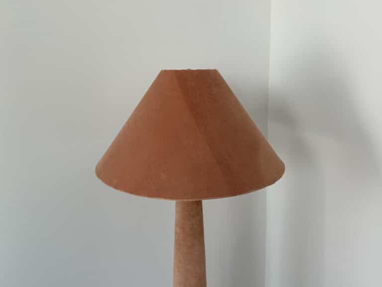 A brown lampshade and lamp base against a plain light-colored wall.