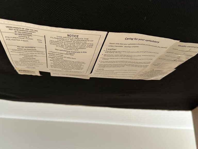 Close-up of upholstery tags with care instructions and material content on the underside of a couch.
