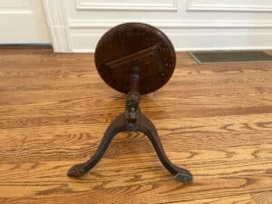 An Antique Side Table, crafted from wood, is positioned on its side on an indoor wooden floor.