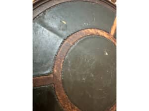 Close-up of the Antique Side Table's circular leather surface with a wood inlay design, showcasing signs of wear and scratches.