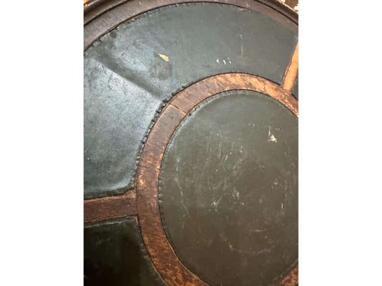 Close-up of the Antique Side Table's circular leather surface with a wood inlay design, showcasing signs of wear and scratches.